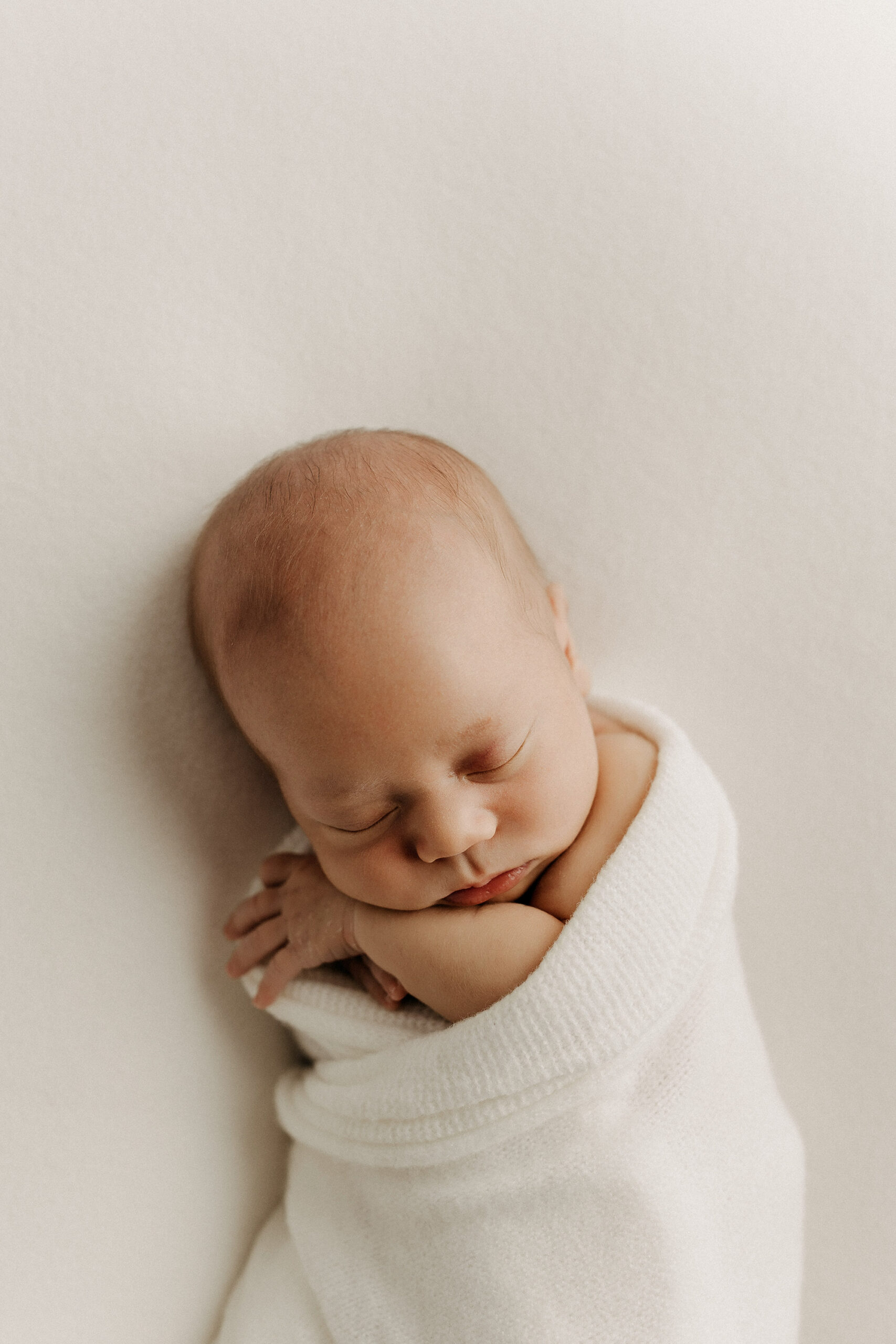 Wrapped newborn baby sleeping peacefully during a natural in-home newborn session in San Diego.