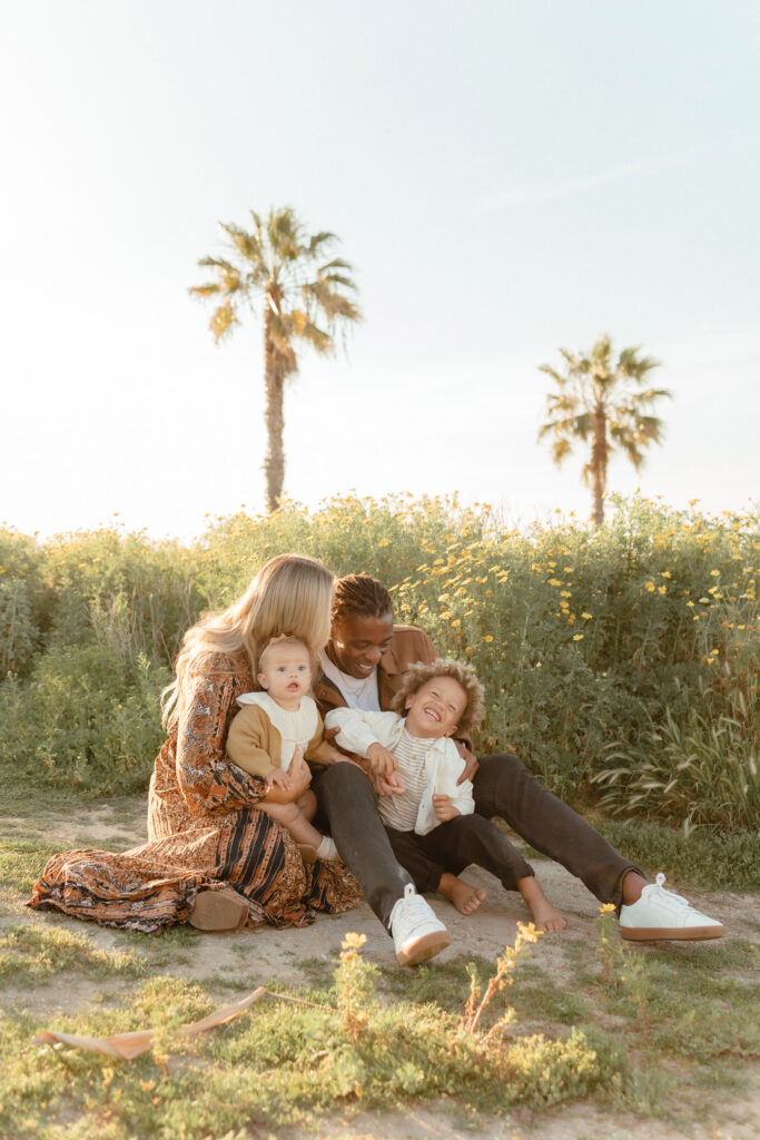San Diego family photos in wildflowers with parents and two children sitting together in golden light