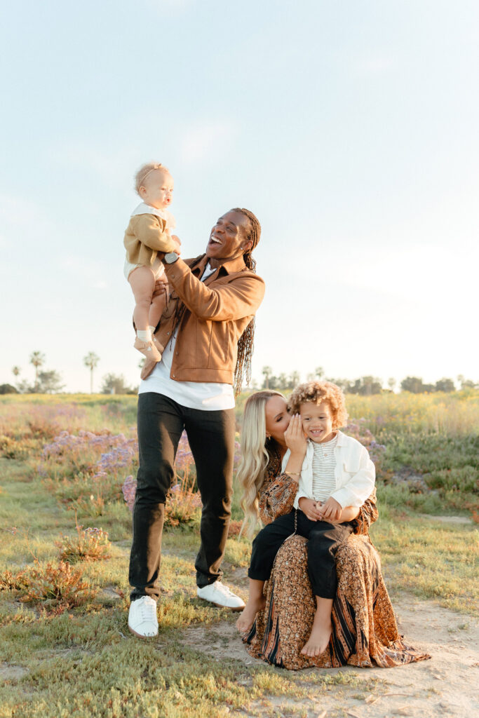 Family photos in wildflowers with parents and two children enjoying golden hour light