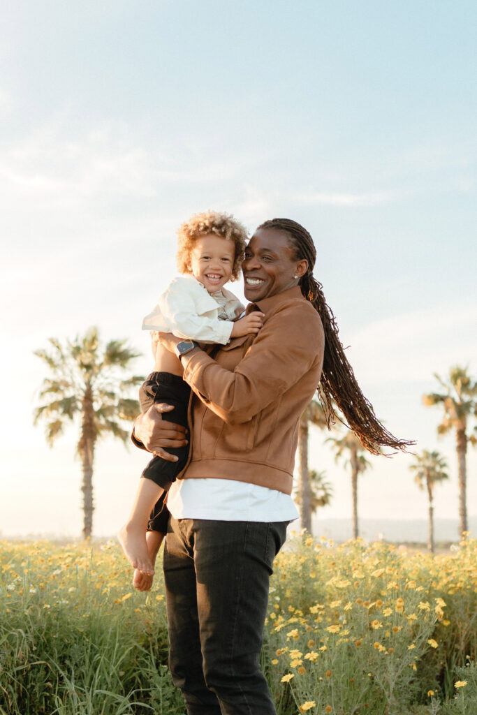San Diego family photographer capturing father holding child in wildflowers during golden hour