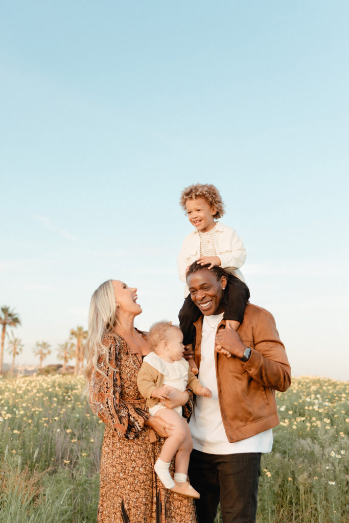 San Diego family photos in wildflowers with parents and children laughing in soft natural light